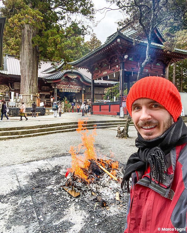 Marco Togni con cappello rosso davanti al fuoco al santuario Kitaguchi Hongu Fuji Sengen.