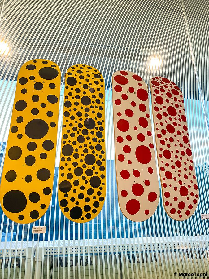 Quattro skateboard con motivi a pois gialli e rossi esposti in una vetrina al Moma Design Store di Tokyo.