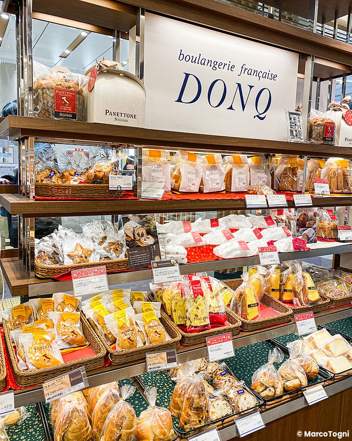 Scaffali di prodotti da forno e panettoni natalizi in vendita presso la panetteria Donq.