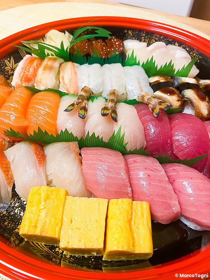 Vassoio rotondo con diversi tipi di sushi colorato.