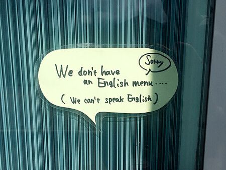 Cartello che indica l'assenza di menu in inglese su una porta di vetro.