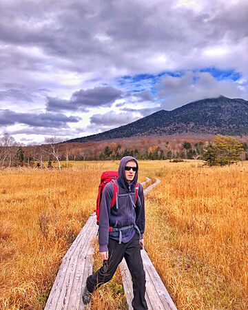 Persona cammina su passerella di legno nel Parco Nazionale di Oze in autunno.