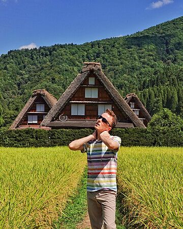 Persona in un campo di riso con case Gassho-zukuri sullo sfondo a Shirakawa-go.