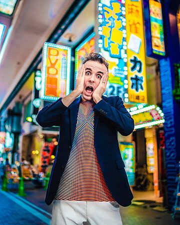 Marco Togni sorpreso in un vicolo illuminato da insegne al neon in Giappone.