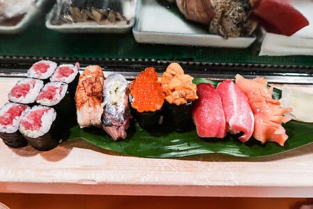 Assortimento di sushi su foglia verde su bancone di legno.