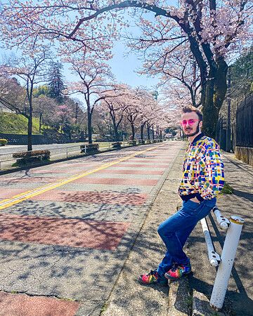 Persona in posa su una strada a tokyo con ciliegi in fiore.