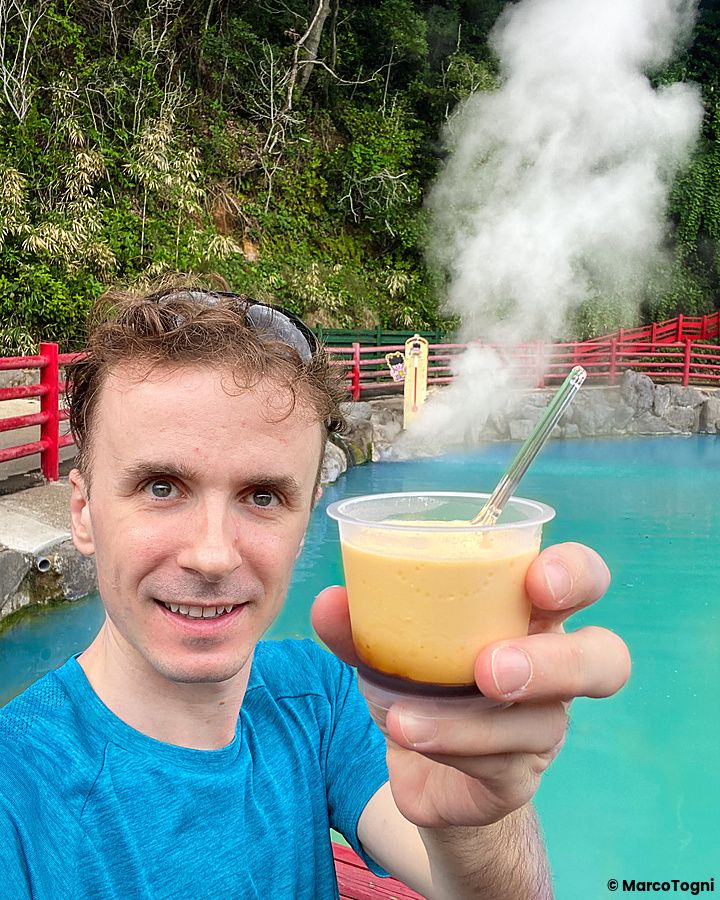 Marco Togni con budino davanti a fonte termale fumante a Beppu.