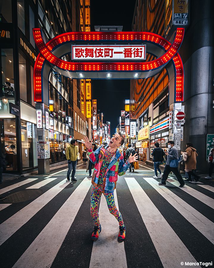 Persona con abito colorato sotto insegna luminosa a Shinjuku.