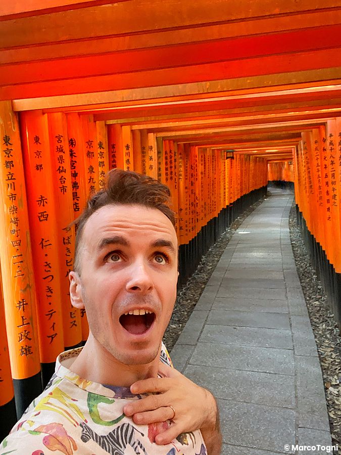 Marco Togni sorpreso sotto i torii rossi del Fushimi Inari a Kyoto.
