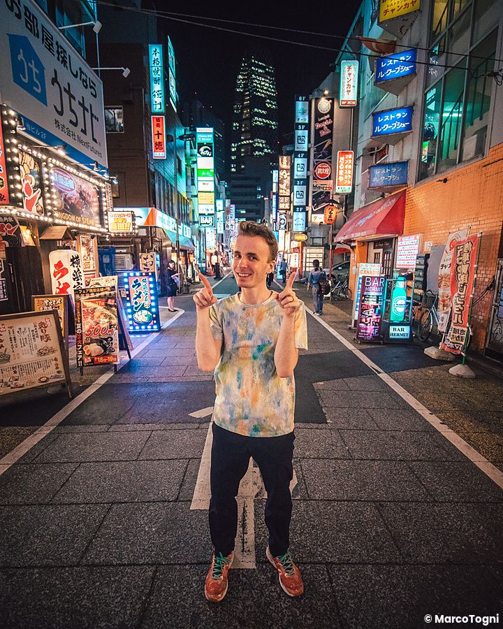 Marco Togni in una strada illuminata a Shinjuku con insegne luminose.