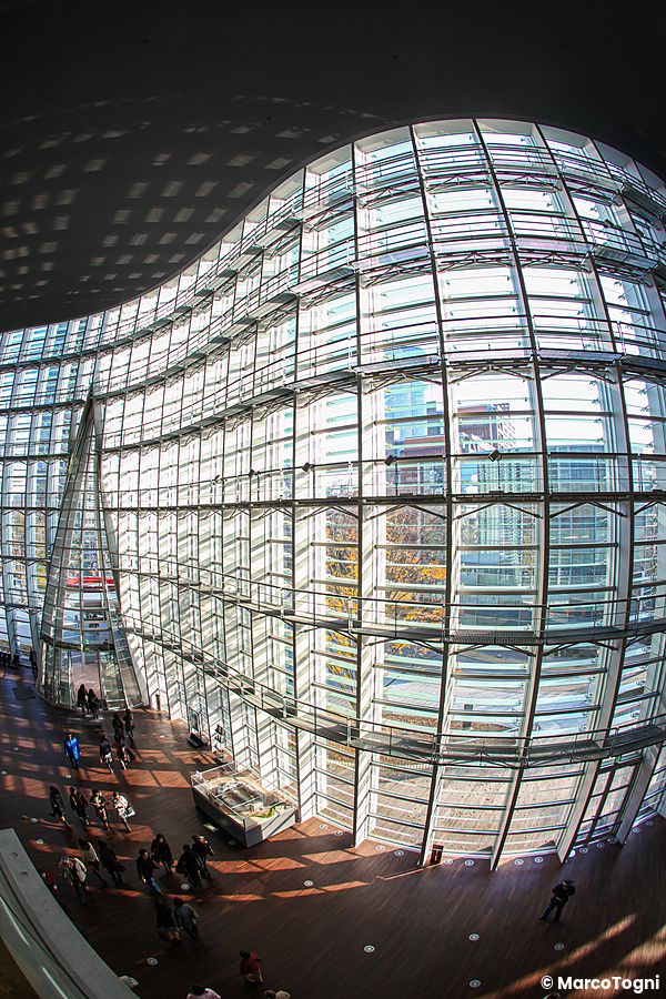 Interni del National Art Center di Tokyo con facciata in vetro e persone presenti.