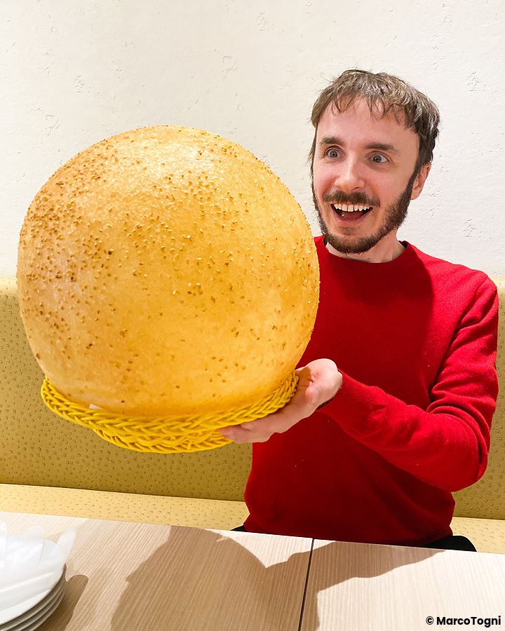 Marco Togni tiene in mano una gigantesca palla fritta al sesamo, un dolce servito al ristorante Mara Daigaku a Ueno.