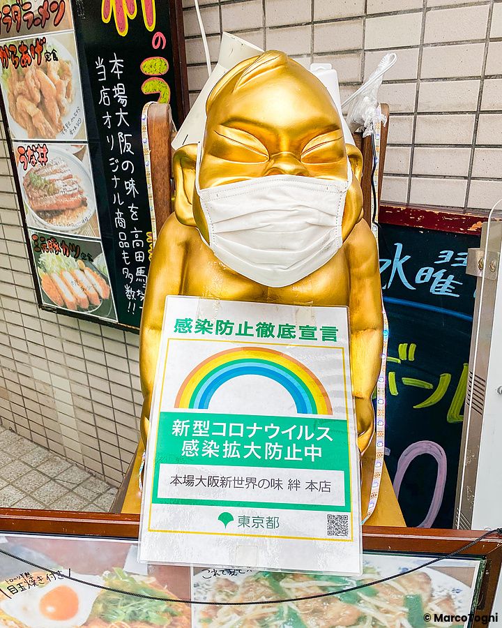 Statua dorata con mascherina e cartello Covid-19 in Giappone.