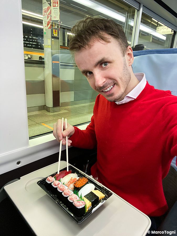 Marco Togni che mangia sushi su un treno giapponese.