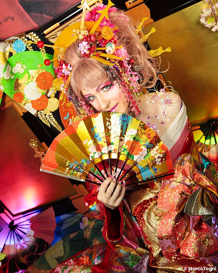 Persona travestita da oiran con ventaglio colorato in abito tradizionale giapponese.