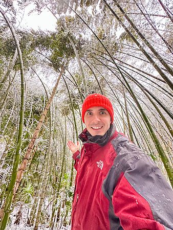 Marco Togni con giacca e berretto rossi in una foresta di bambù innevata in Giappone.