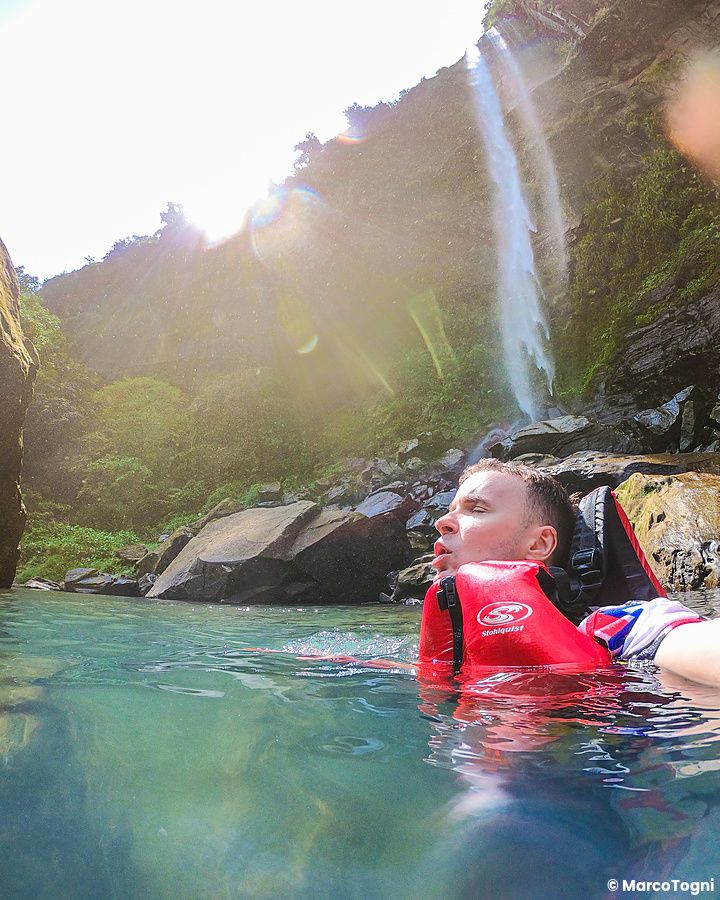 Marco Togni con giubbotto di salvataggio nuota nelle acque limpide davanti alle Cascate di Pinaisara sull'isola Iriomote.