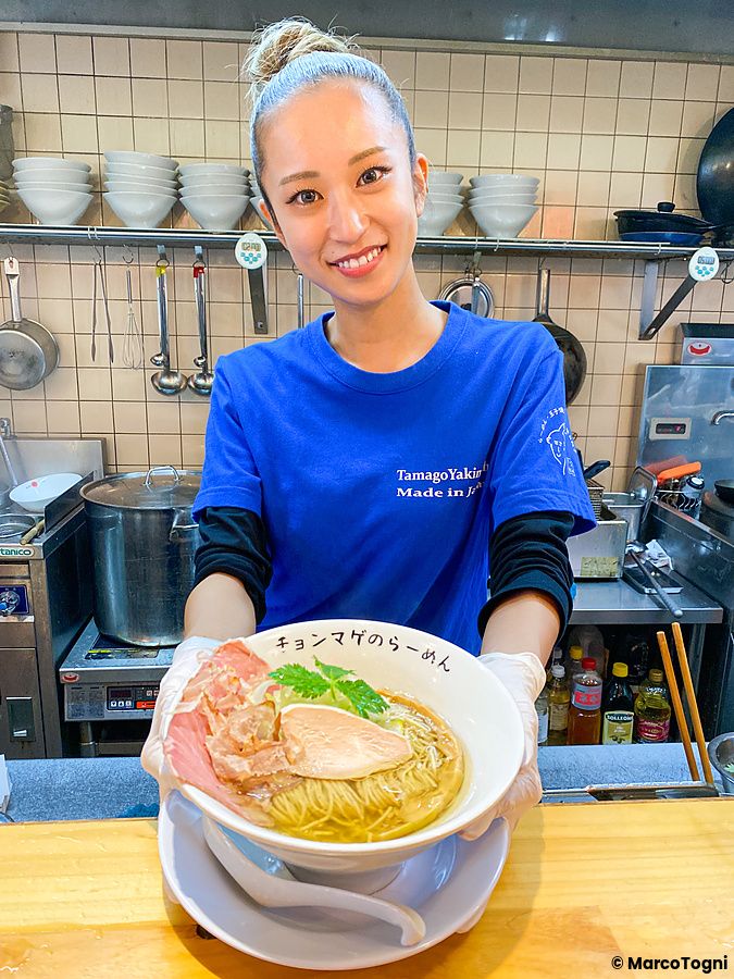 La chef a Ramen Chonmage Osaka Tenroku Ten sorride tenendo una ciotola di ramen preparata nel ristorante.