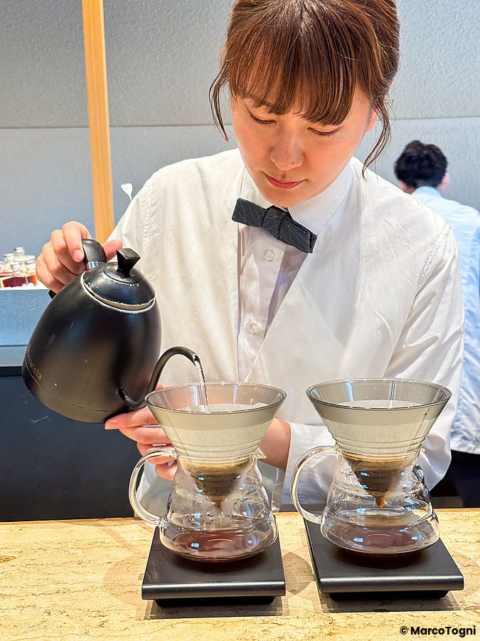 Una barista prepara un caffè filtrato versando acqua in una caraffa presso Koffee Mameya Kakeru a Tokyo.