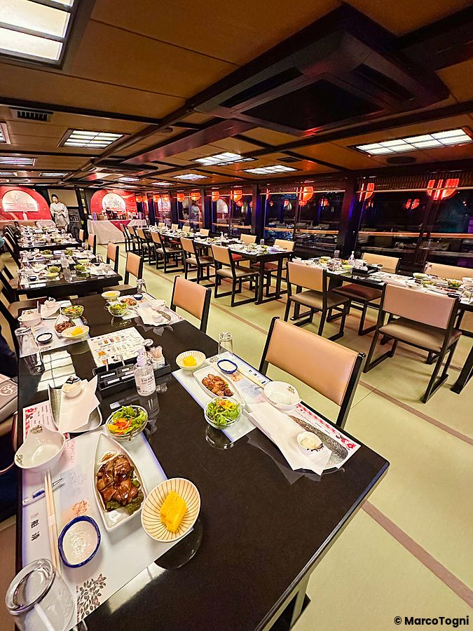 Interno di una Yakatabune a Tokyo con tavoli allestiti per una cena lungo il fiume su pavimentazione in tatami.