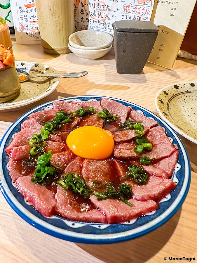 Un piatto di manzo crudo con tuorlo d'uovo e cipollotto servito presso l'izakaya Shibuya Kito Kito a Shibuya.
