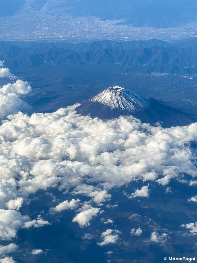 vista aerea del monte Fuji con neve sulla cima, circondato da nuvole.