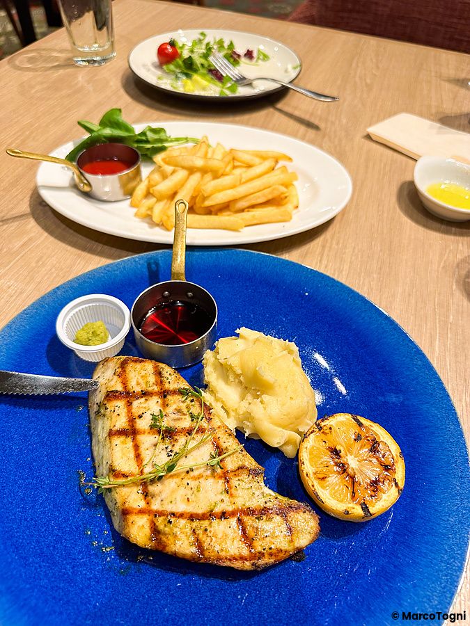 Un piatto con pollo a Sizzler grigliato, purè di patate e limone su un tavolo di legno nel ristorante Sizzler.