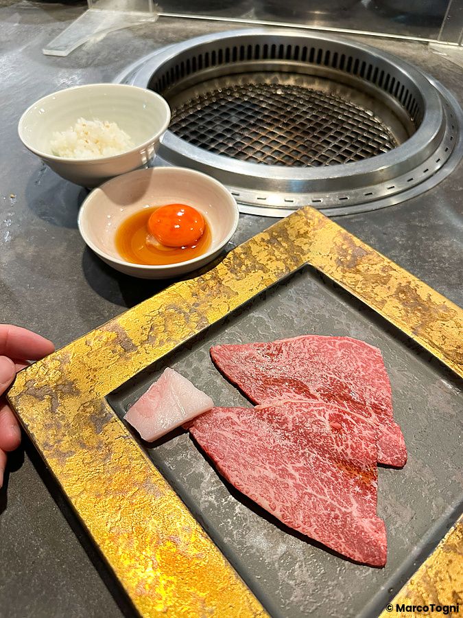 Carne cruda e una ciotola di uovo con salsa su un tavolo del ristorante di yakiniku Han no Daidokoro a Shibuya.