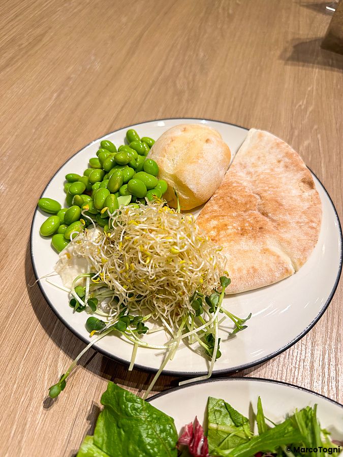 Un piatto con edamame, germogli e pane servito in un ristorante Sizzler.