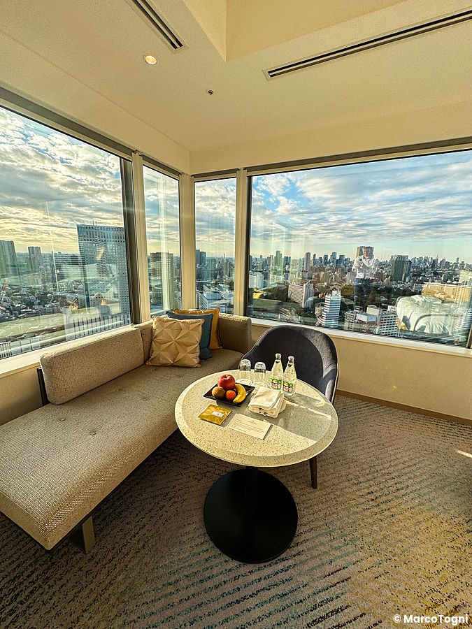 Una corner room al InterContinental the Strings Tokyo con vetrate panoramiche sullo skyline e un tavolo con frutta.
