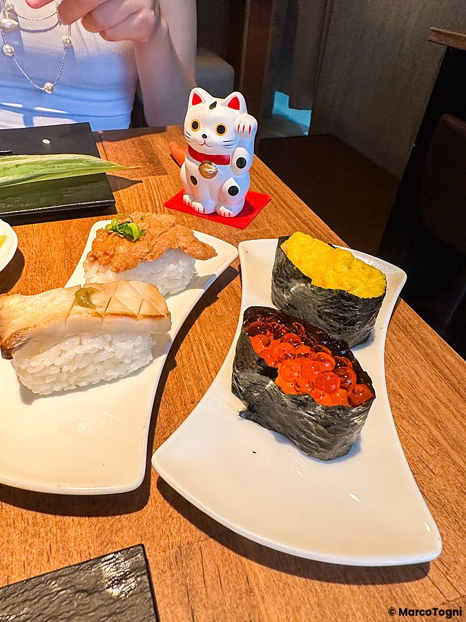 Piatti di sushi vegano serviti su un tavolo in legno presso il ristorante Vegan Sushi Tokyo a Shibuya con un maneki-neko.