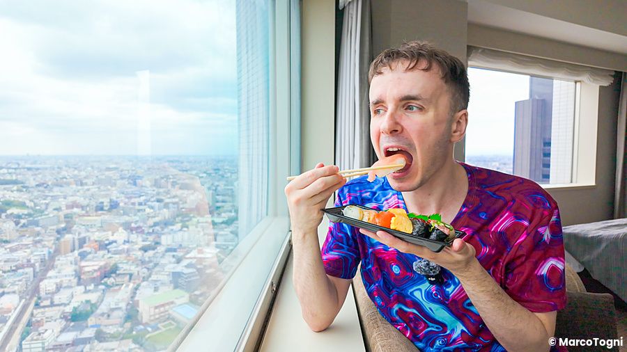 Marco Togni che mangia sushi con vista sulla città di Tokyo.