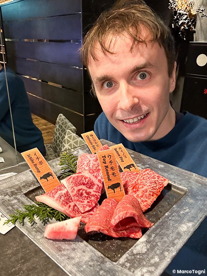 Marco Togni sorridente mostra un vassoio di tagli pronti da cucinare a Han no Daidokoro nel ristorante di Shibuya.