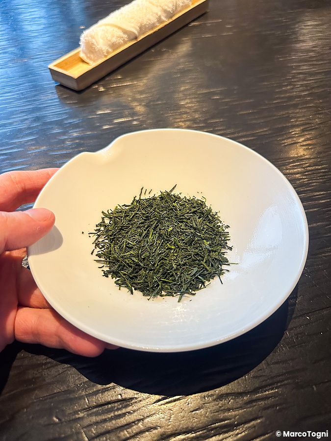 Una mano sostiene un piattino bianco con foglie di tè verde essiccate presso il Sakurai Japanese Tea Experience a Tokyo.