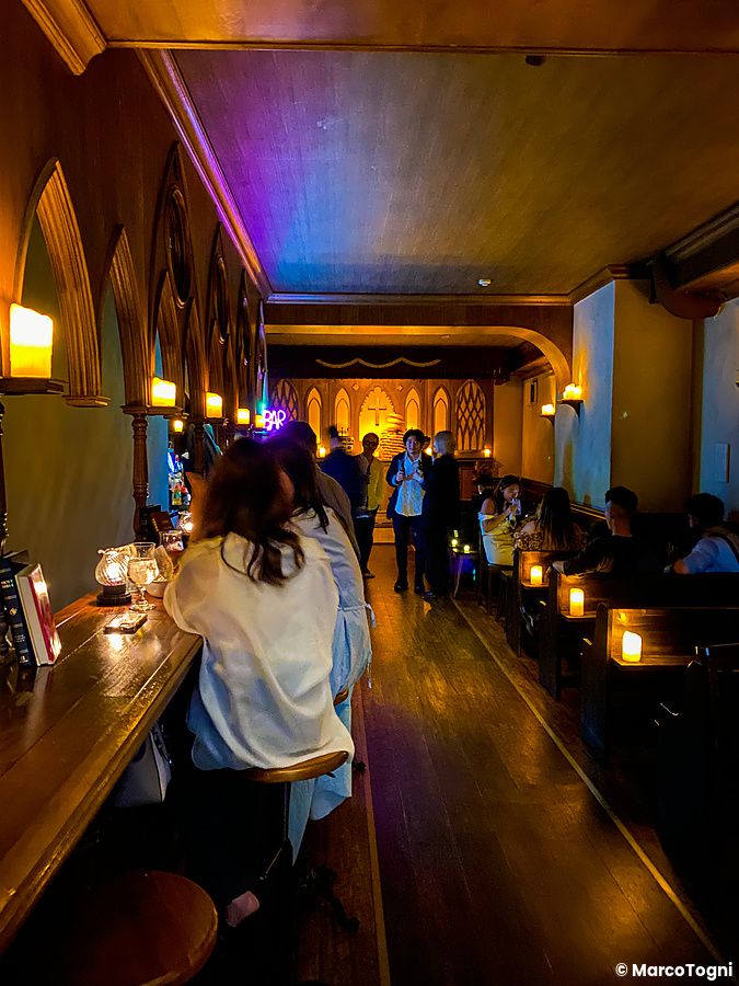 Interno del bar The Church a Shibuya con arredamento in stile chiesa e persone sedute al bancone.