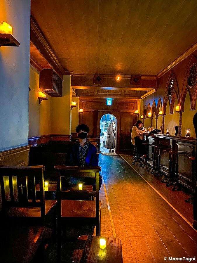 Interno del bar The Church a Shibuya con arredi in legno, luci soffuse e una persona seduta in primo piano.