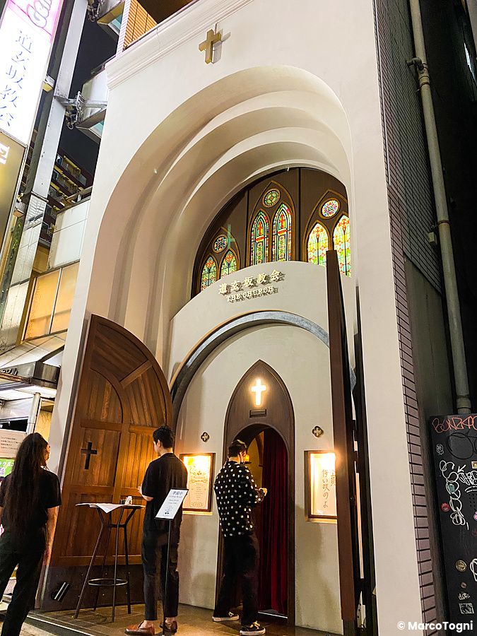 L'ingresso serale del bar a tema The Church a Shibuya, con facciata bianca e vetrate colorate.
