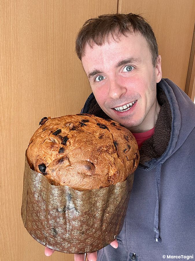 Marco Togni sorridente tiene in mano un panettone della panetteria DonQ a Tokyo all'interno di una casa in Giappone.