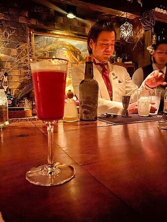Hiroyasu Kayama prepara drink dietro il bancone di legno al Bar Benfiddich a Shinjuku, Tokyo.