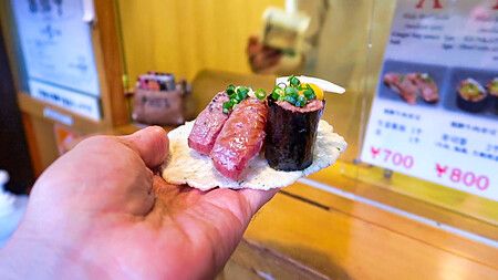 Sushi di carne di Hida su cialda di riso tenuto in mano.