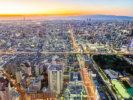 Vista panoramica di Osaka al tramonto dalla stanza angolare di un hotel.