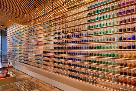 Parete con centinaia di barattoli di pigmenti colorati disposti su scaffali di legno nel negozio Pigment a Tokyo.