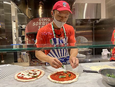 Un pizzaiolo prepara pizze su un bancone presso la Pizzeria Gino Sorbillo a Tokyo.