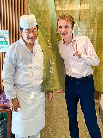 Uno scatto di Marco Togni insieme allo chef in divisa davanti alla tenda noren presso il ristorante Tempura Kondo.