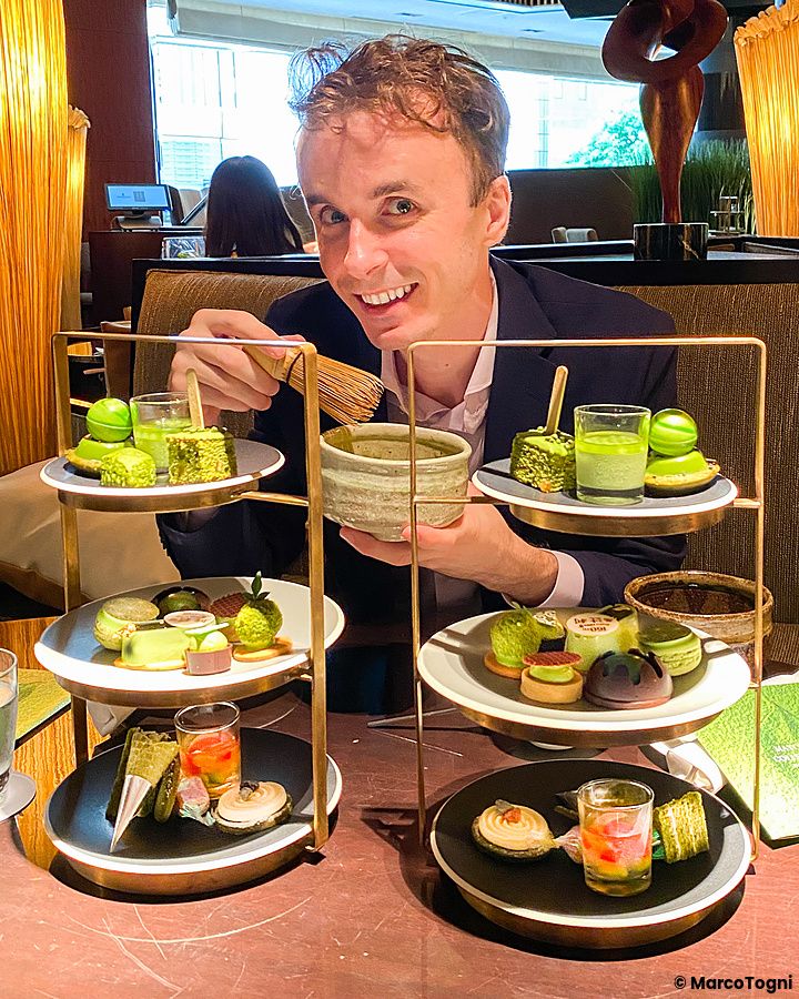 Marco Togni sorridente tiene una ciotola di tè e un frustino di bambù durante un afternoon tea gusto matcha a Atrium Lounge.
