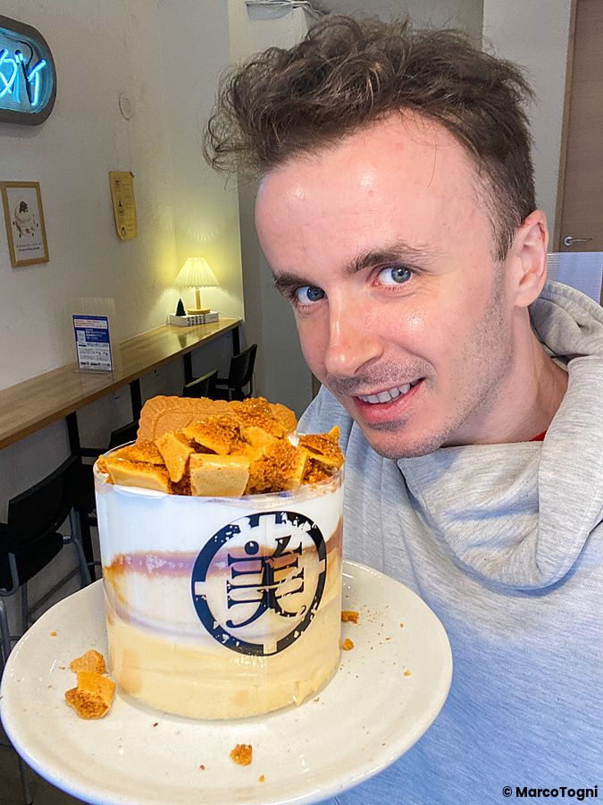 Marco Togni sorridente tiene in mano un piatto con un pancake al biscotto Lotus servito al Belle Epoque.