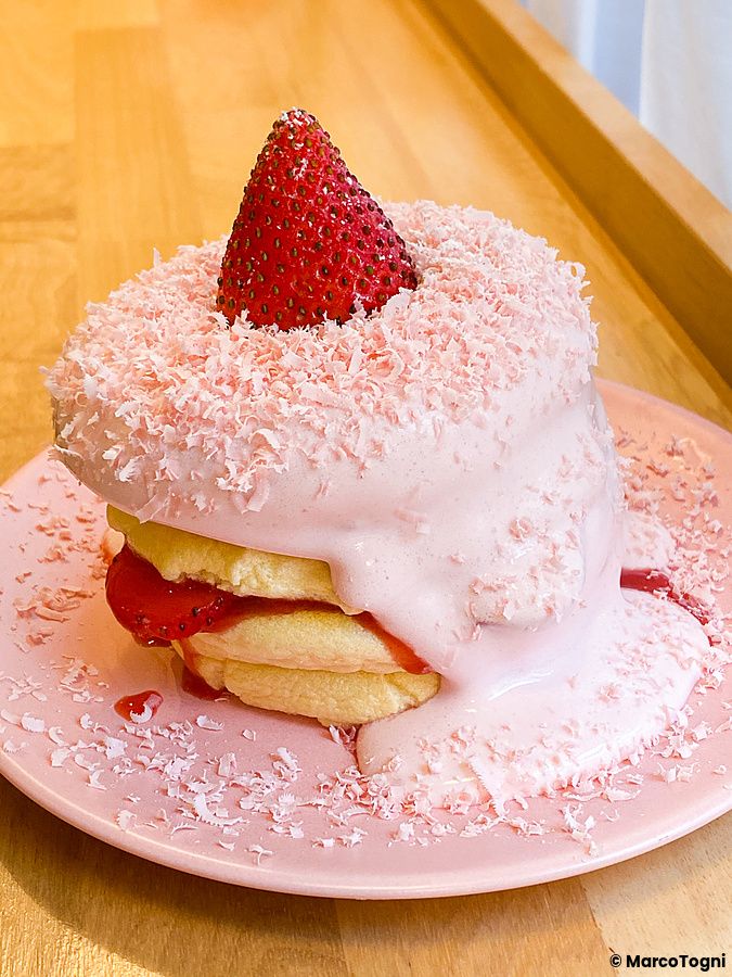Un pancake alla fragola guarnito con crema rosa e una fragola intera, servito in un piatto rosa da Belle Epoque.