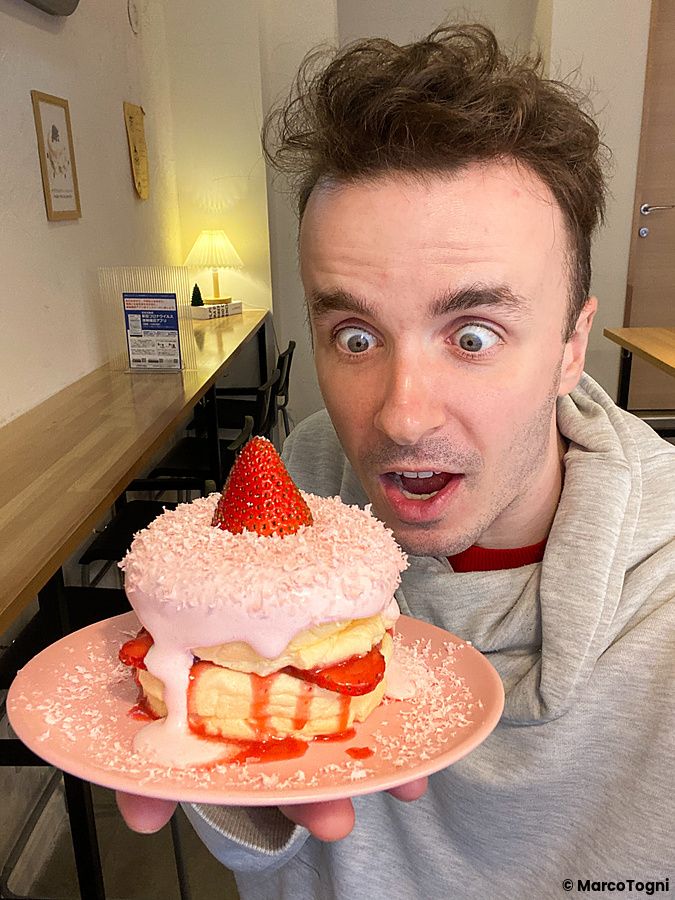 Marco Togni guarda con espressione sorpresa un pancake alla fragola servito su un piatto rosa presso il Belle Epoque.