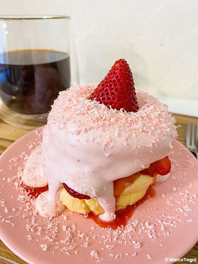 Un pancake alla fragola con crema rosa e scaglie di cioccolato servito su un piatto rosa al ristorante Belle Epoque.
