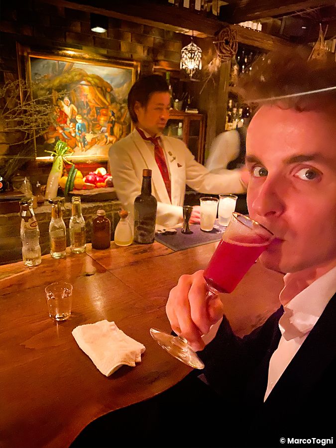Marco Togni beve un cocktail al Bar Benfiddich a Tokyo mentre un barman Marco Togni in giacca bianca lavora dietro il banc...